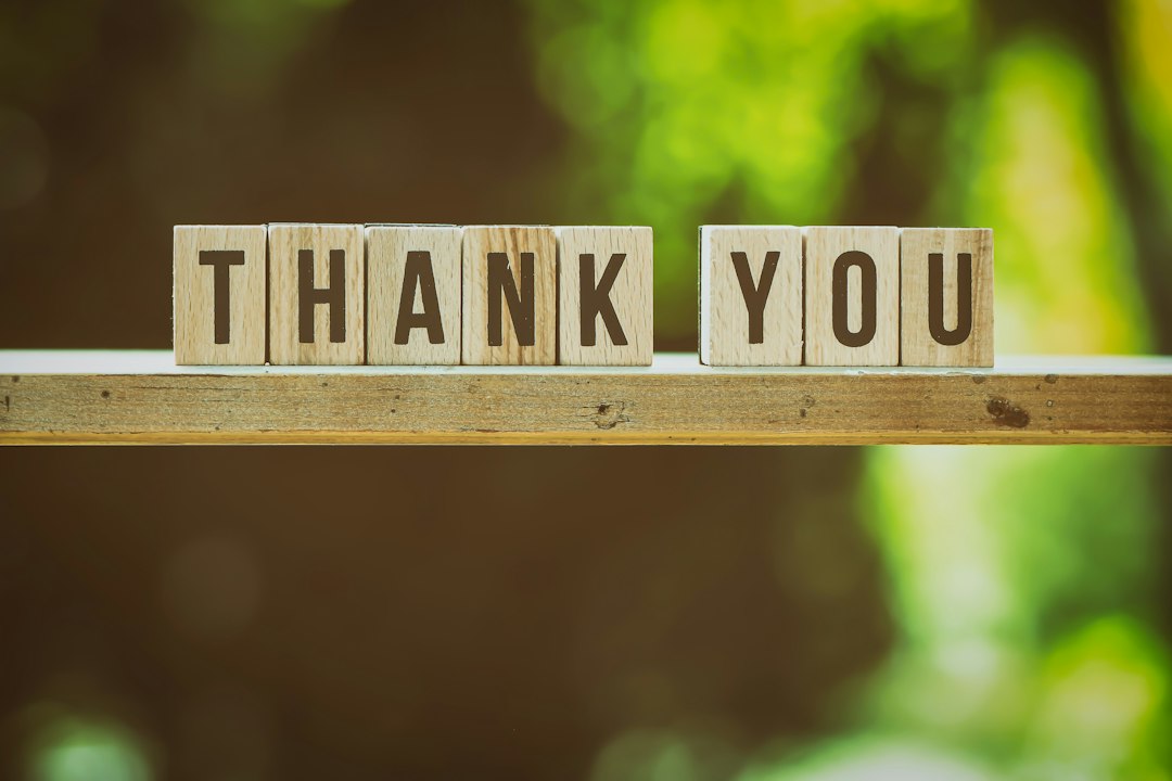 Wooden blocks spelling thank you against a green background